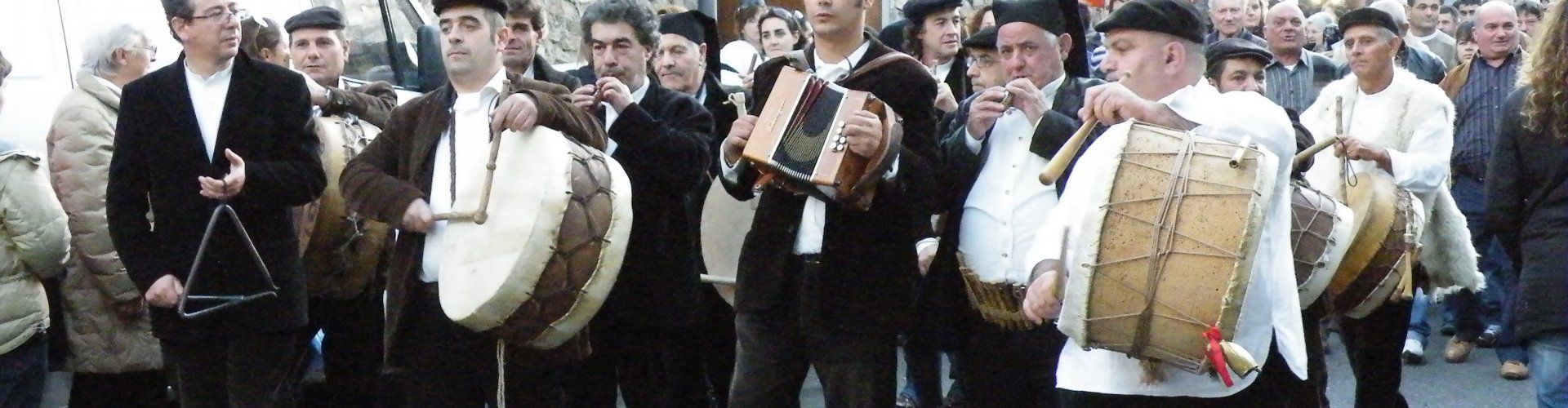 Männer in dunklen Samtanzügen, weißen Hemden und mit sardischen Berittas spielen traditionelle Instrumente beim Orangenfest in Muravera