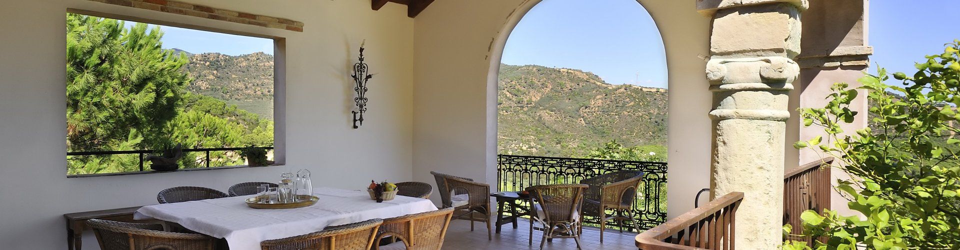 Überdachte Terrasse mit großem Esstisch und Blick in die Natur