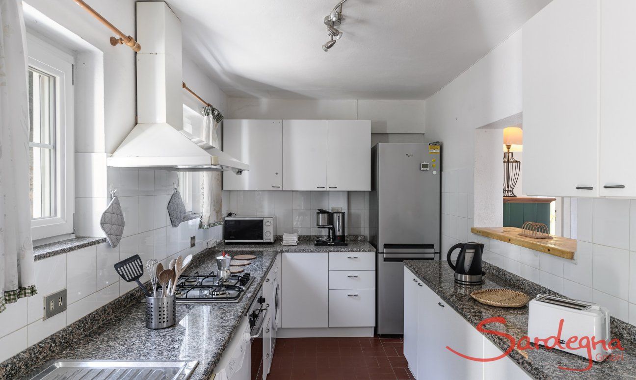 Villa Bau Cannas | Große, vollausgestatte Küche mit viel Tageslicht und Durchreiche zum Wohnzimmer Villa Bau Cannas Torresalinas Sardinien