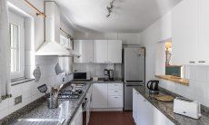 Villa Bau Cannas | Große, vollausgestatte Küche mit viel Tageslicht und Durchreiche zum Wohnzimmer Villa Bau Cannas Torresalinas Sardinien