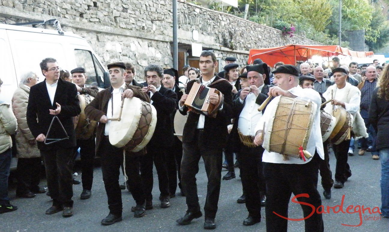 Männer in dunklen Samtanzügen, weißen Hemden und mit sardischen Berittas spielen traditionelle Instrumente beim Orangenfest in Muravera