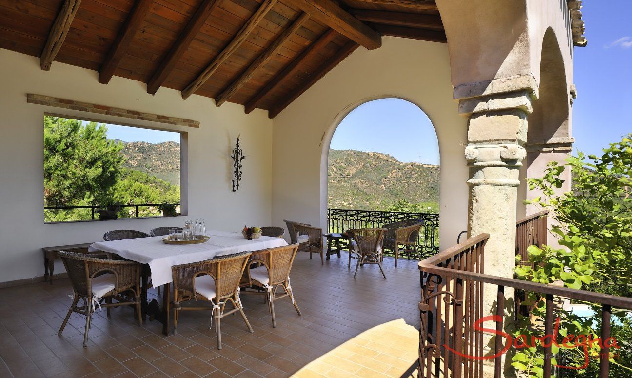 Überdachte Terrasse mit großem Esstisch und Blick in die Natur