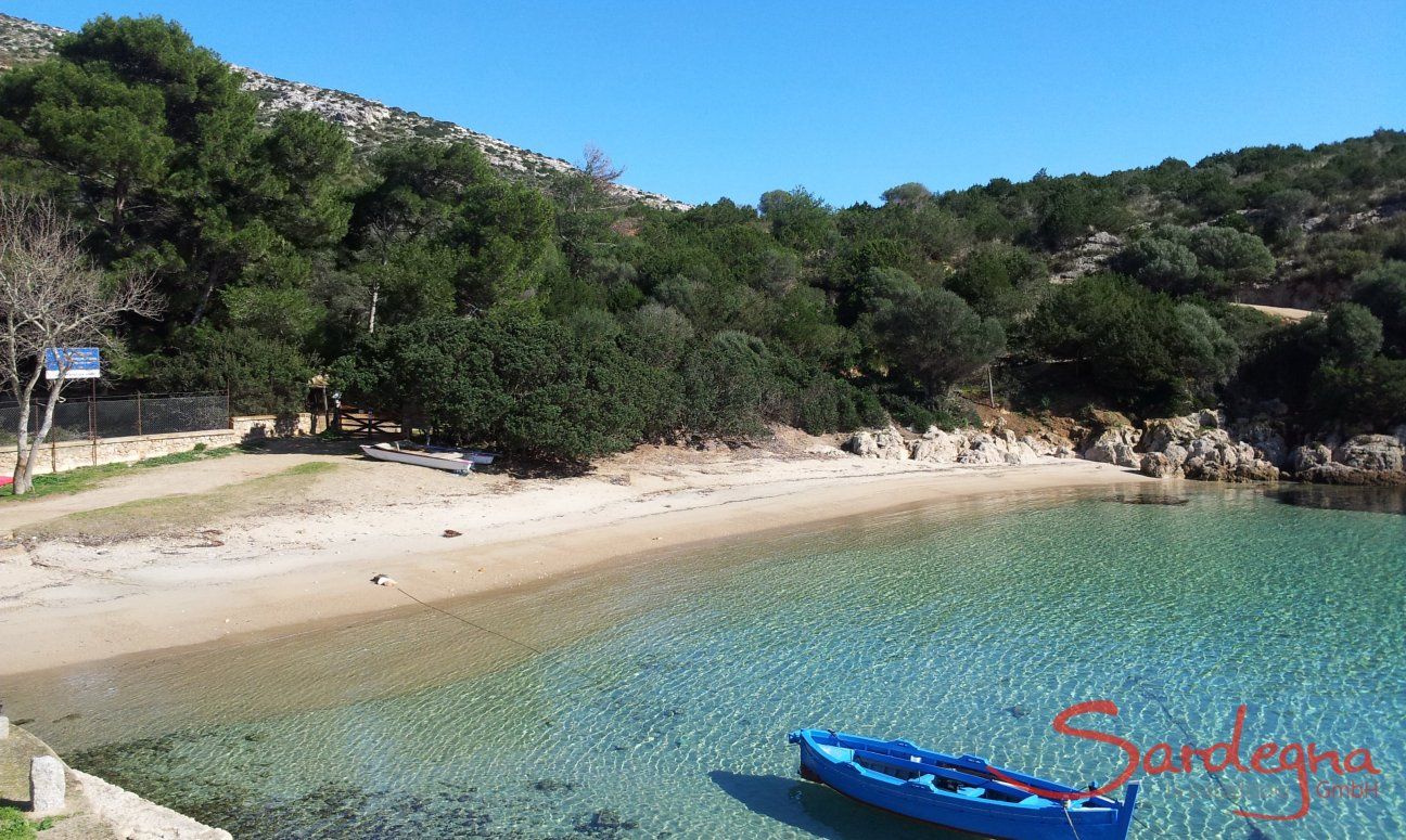 Blaues Fischerboot schwebt im glasklaren Wasser der Bucht Cala Moresca bei Golfo Aranci