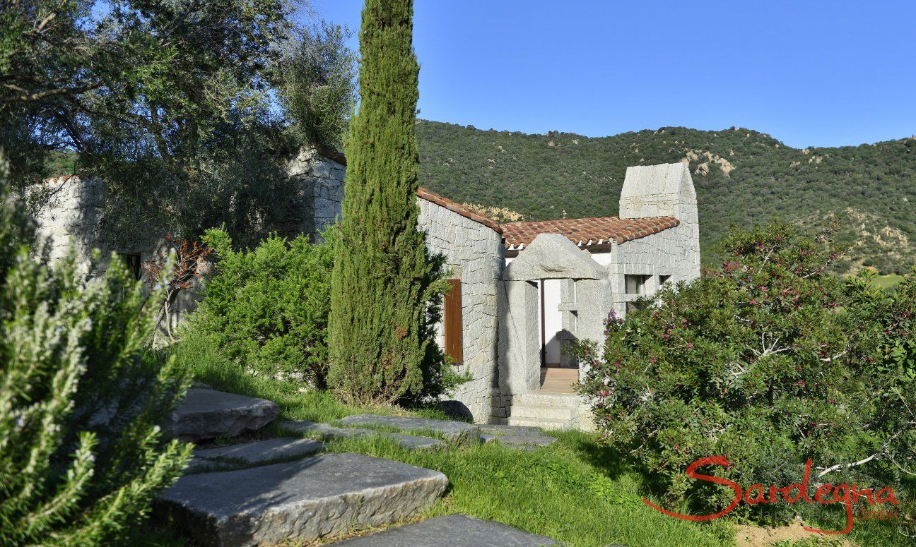 Li Conchi 1 | Zugang zum Granithaus umgeben von grünen Pflanzen Sardinien