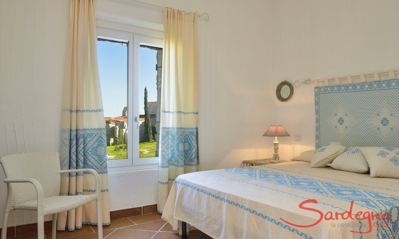 Li Conchi 9 | Schlafzimmer 1 mit Doppelbett und Gartenblick Schlafzimmer mit Doppelbett mit hellblau dekorierten sardischen Stoffen Li Conchi 9, Cala Sinzias
