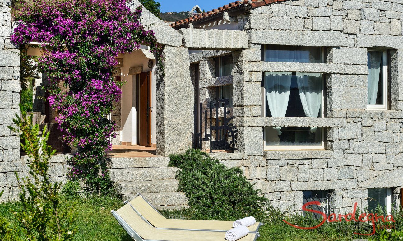 Li Conchi 15 | Haus aus Granit mit grünem Garten und lila blühendem Bougainville Hausansicht