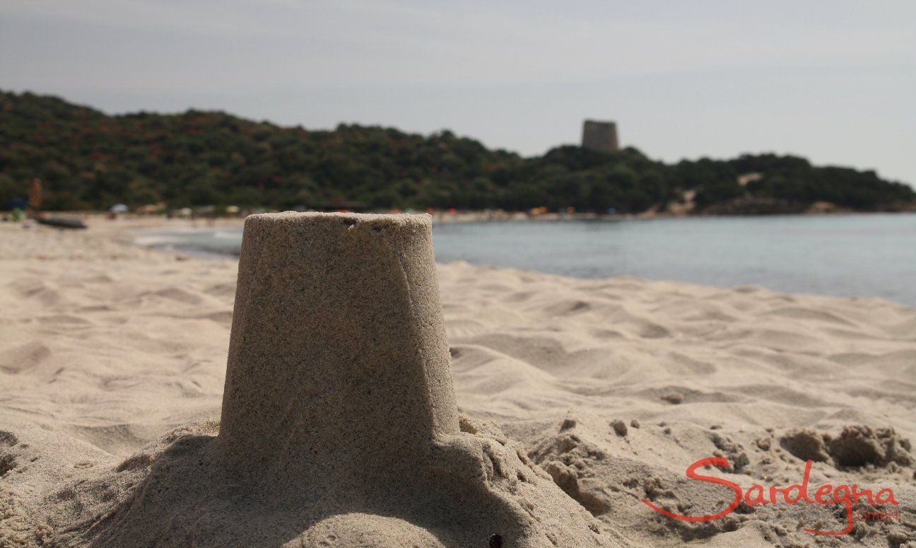 Mit Sand nachgebauter spanischer Wachturm von Cala Pira im Vordergrund, im Hintergrund der echte Turm