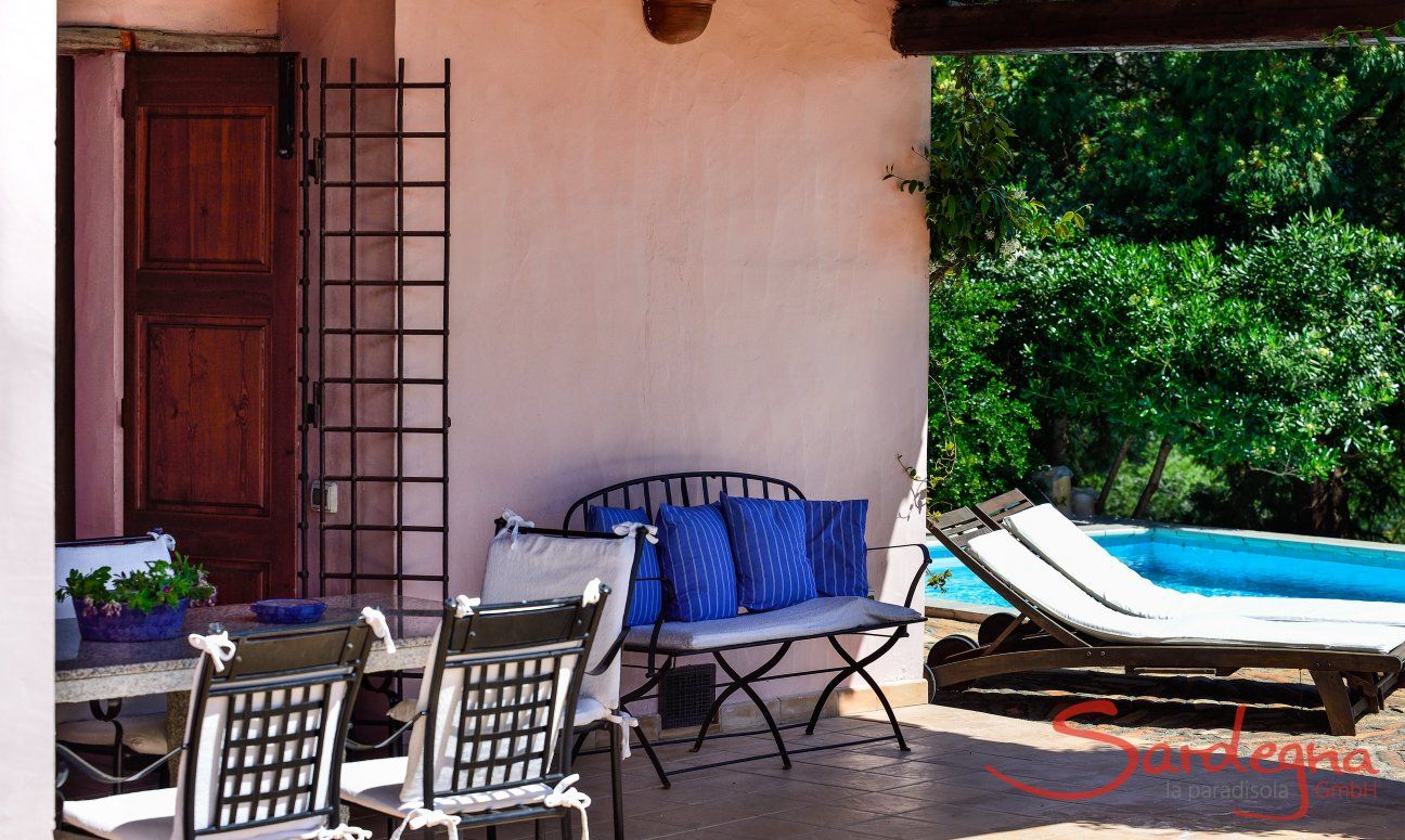 Überdachte Terrasse mit Esstisch aus Granit und Blick zum Pool