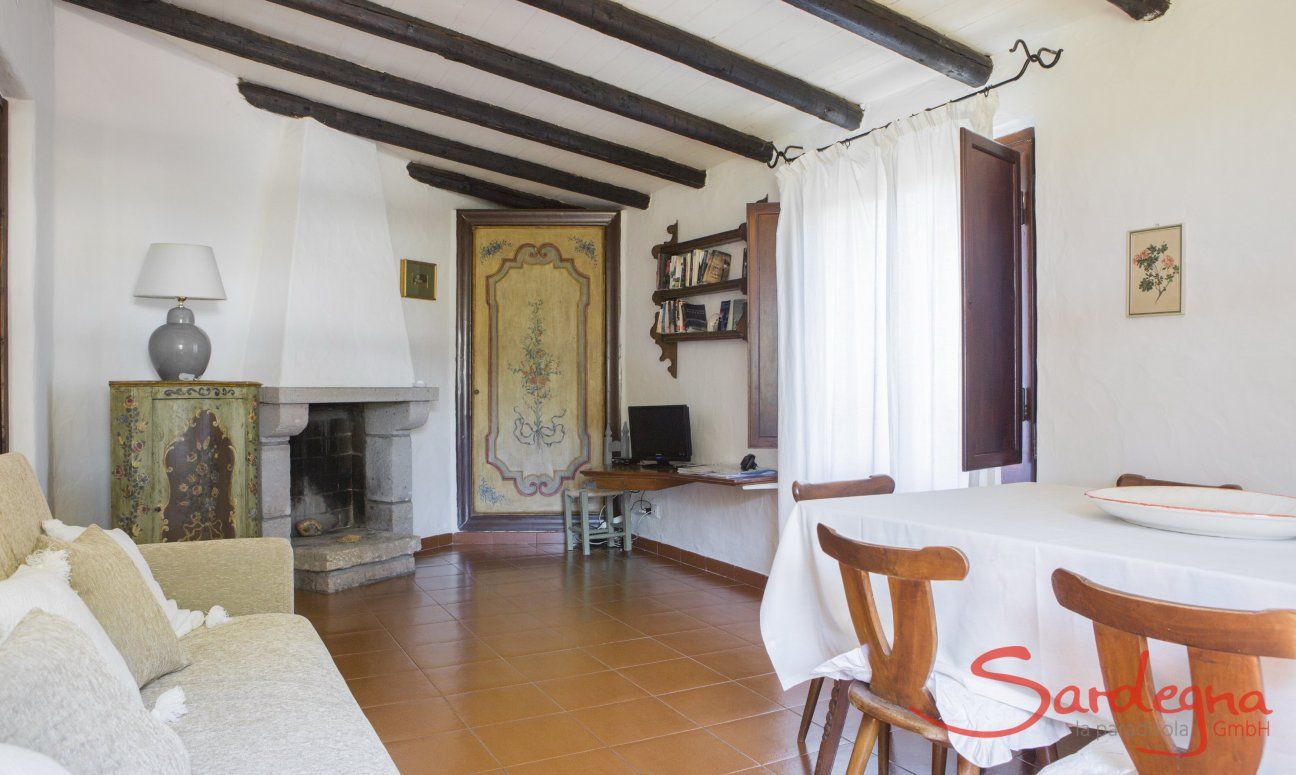 Casa Su Faru 5 | Im Landstil eingerichtetes Wohnzimmer mit Esstisch, Sofa, Kamin und TV Sardisch eingerichtetes Wohnzimmer mit Esstisch und Kamin