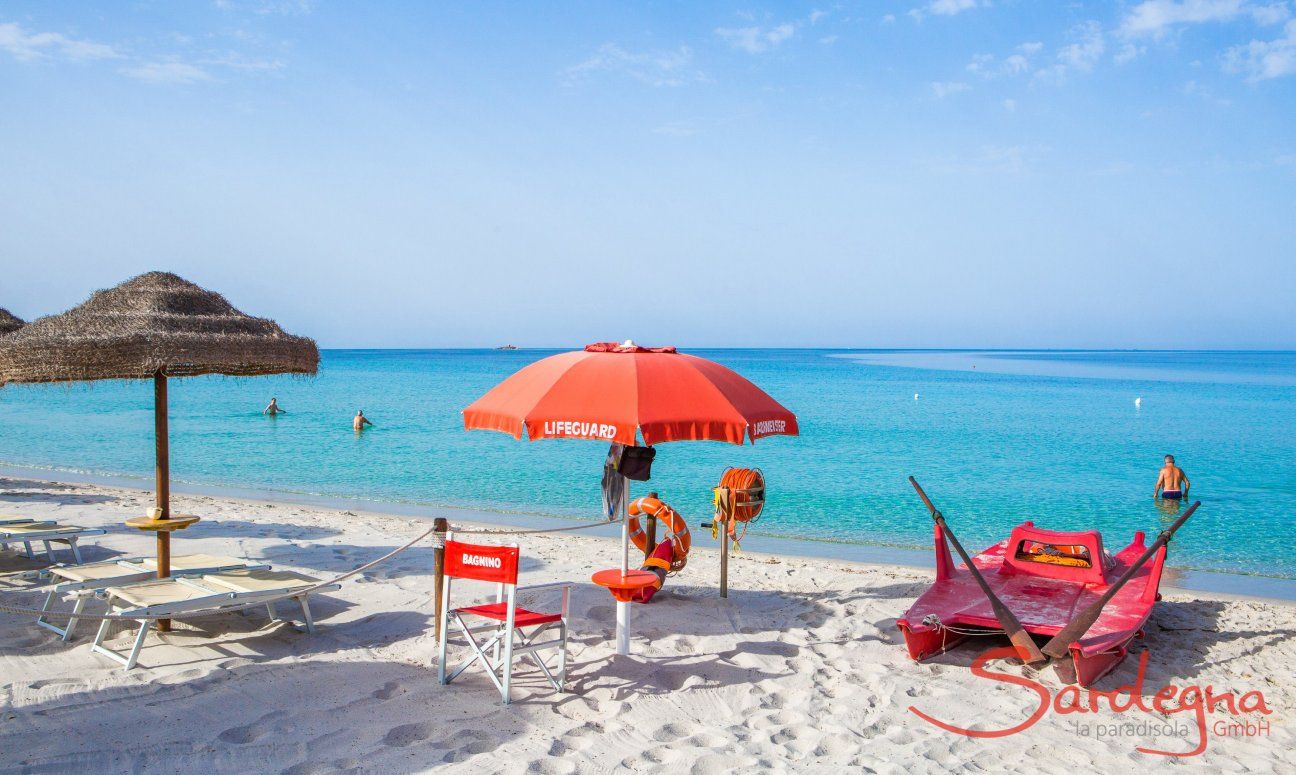 Bademeisterposten mit rotem Stuhl, Schirm und Floß am kalkweißen Strand