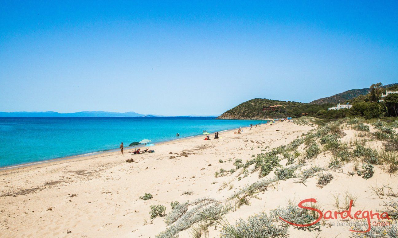 Breiter weißer Sandstrand von Geremeas mit blauem Meer und der Küste von Cagliari im Hintergrund