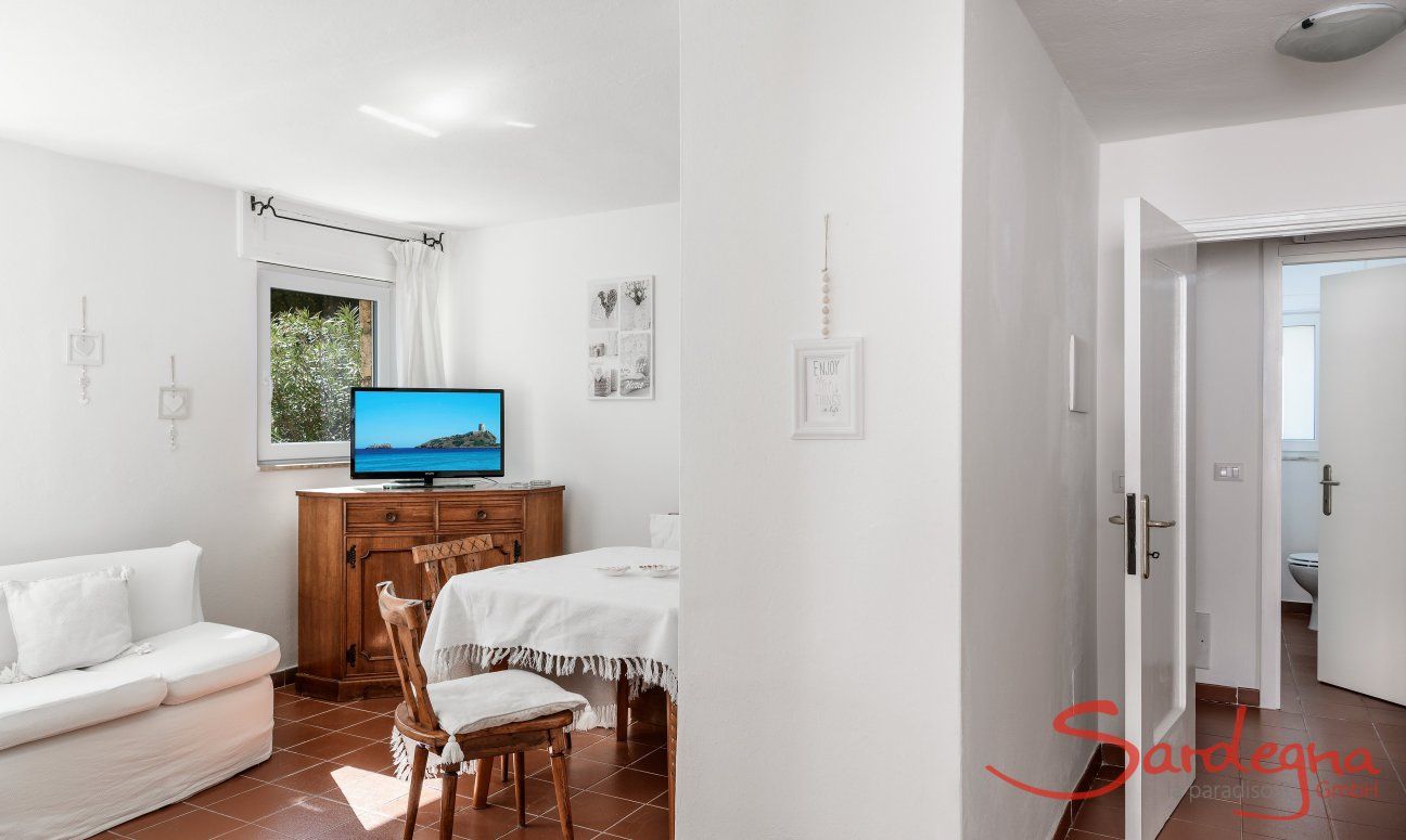 Casa Su Faru 3 | Wohzimmer mit Sofa, Esstisch, TV und Zugang zu zweien der drei Schlafzimmern Wohzimmer mit Sofa, Esstisch, TV und Zugang zu den Zimmern von Su Faru 3 Pula