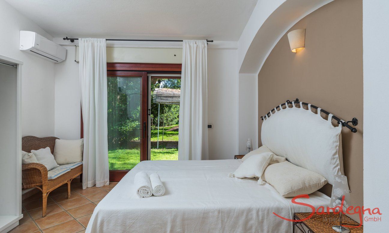 Apartment Orri 1 | Schlafzimmer 1 mit Doppelbett und Tür zum Garten Orri 1, Tortoli, Ostsardinien