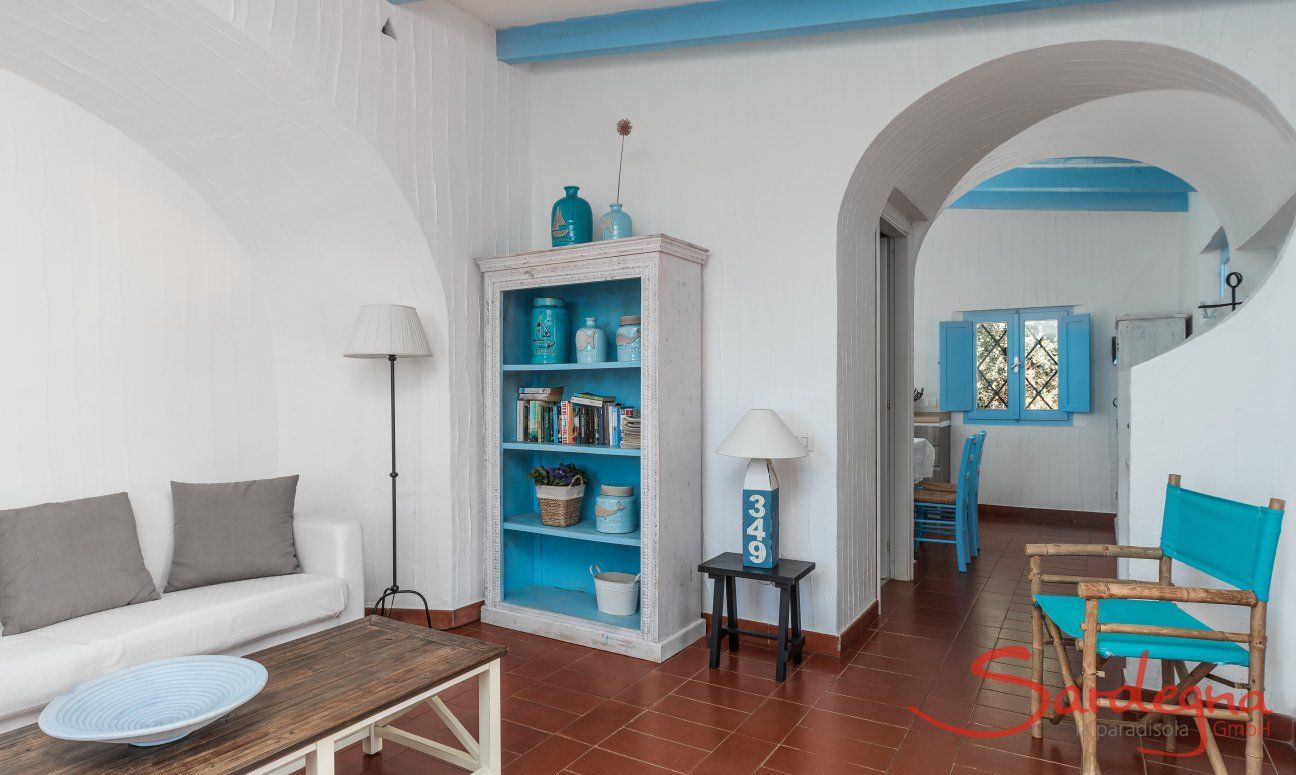 Casa 17 | Wohzimmer mit elegantem Sofa und praktischem Bücherregal, Torbogen zur Wohnküche Casa 17, Sant Elmo, Südsardinien