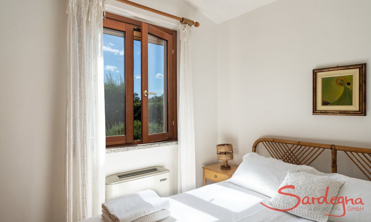 Villa Tiziana 11 | Schlafzimmer 1 mit Doppelbett, Klimaanlage und Blick ins Grüne Hausdarstellung