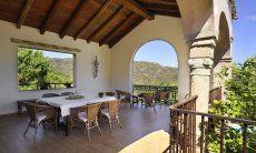 Überdachte Terrasse mit großem Esstisch und Blick in die Natur