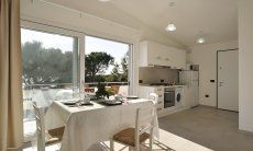 Apartment Cala Liberotto II | Essbereich mit offener Küche und Glasfront Essbereich mit offener Küche und Glasfront