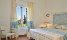 Schlafzimmer mit Doppelbett mit hellblau dekorierten sardischen Stoffen Li Conchi 9, Cala Sinzias
