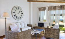 Li Conchi 9 | Moderne Sofaecke mit Meerblick zum entspannen Sofa vor großer Wanduhr und Panoramafenster Li Conchi 9, Cala Sinzias