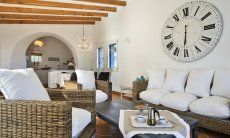 Li Conchi 10 | Sofaecke mit großer Wanduhr und Essbereich im Hintergrund Sofaecke unter einer großen Wanduhr Li Conchi 10, Cala Sinzias