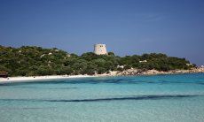 Glasklares Meer, weißer Strand und spanischer Wachtrum in der Bucht Cala Pira