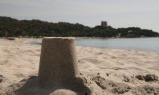 Mit Sand nachgebauter spanischer Wachturm von Cala Pira im Vordergrund, im Hintergrund der echte Turm