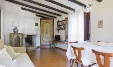 Casa Su Faru 5 | Im Landstil eingerichtetes Wohnzimmer mit Esstisch, Sofa, Kamin und TV Sardisch eingerichtetes Wohnzimmer mit Esstisch und Kamin