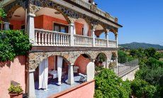 Apartment Castededdu 4 | Lage der Wohnung: grau geflieste Terrasse im Vordergund mit Tisch, Sonnenliegen und Dusche Lage der Wohnung