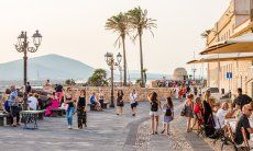 Ufermpromenade von Alghero mit alten Kanonen, hohen Palmen und Blick auf die Küste