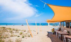 Die Snackbar Il Defino am Strand Feraxi mit schattenspendendem, gelben Sonnensegel