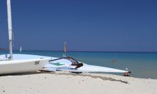 Surfbrett und Laser am Strand von Cala Sinzias