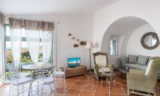 Li Conchi 30 | Wohnzimmer mit Panoramafenster, rundem Tisch mit Stühlen, TV und Sofaecke unter einem großen Wandbogen Hausdarstellung von Li Conchi 30