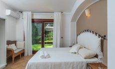 Apartment Orri 1 | Schlafzimmer 1 mit Doppelbett und Tür zum Garten Orri 1, Tortoli, Ostsardinien
