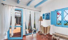 Casa 17 | Wohnzimmer mit Fensterfront zur Terrasse und zum Meer und Lesesessel Casa 17, Sant Elmo, Südsardinien