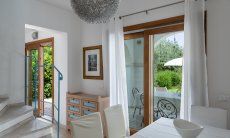 Villa del Campo | Wohnzimmer und Küche haben große Fenstertüren zur Terrasse und zum Pool Villa del Campo, Is Molas, Pula