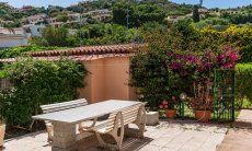 Villa Palme | Großer, stabiler Granittisch inmitten blühenden, mediterranen Planzen mit Blick auf die Hügel von Costa Rei Villa Palme, Costa Rei