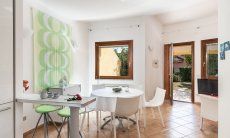 Villa Sandra 43 | Küchentheke und runder Esstisch, Tür zum Garten Hausdarstellung